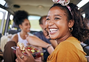 Woman smiling while eating lunch in car