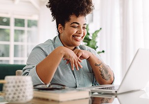 Woman smiling while working on laptop at home