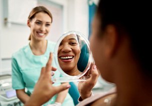Patient smiling at reflection in treatment chair