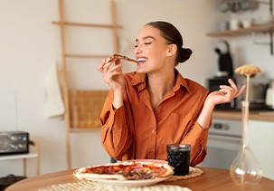 Woman enjoying slice of pizza at home