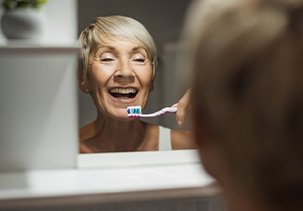 A woman brushing her dental implants