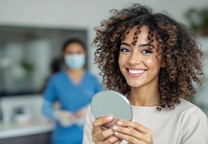 Woman smiling while holding small mirror