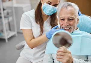 A man looking at his dental implants with his dentist
