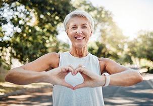 Lady smiles while making shape of heart with her hands