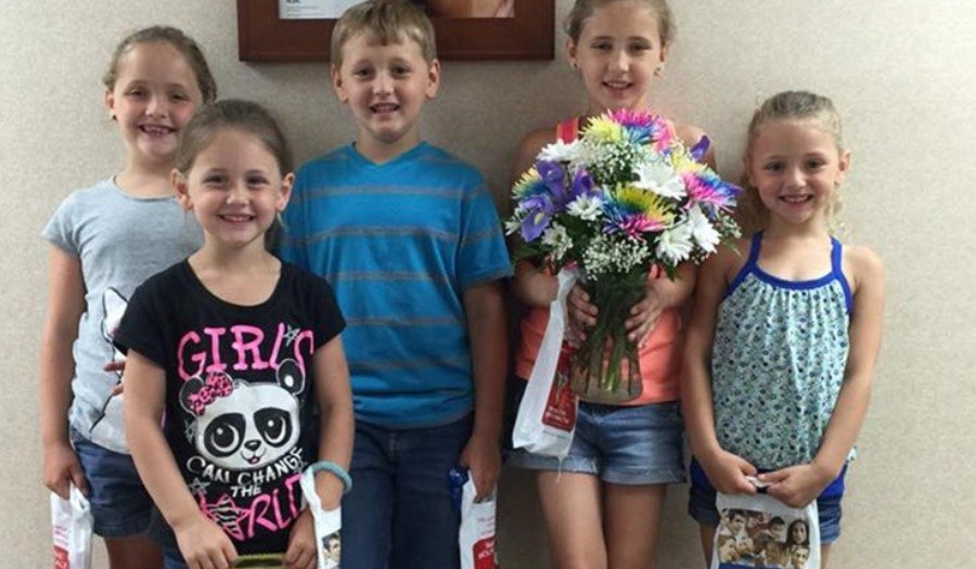 Group of smiling children holding flowers in dental office