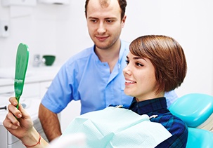 Dental patient looking at her smile in mirror