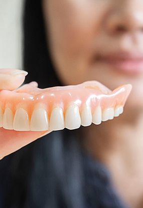 a woman holding a denture