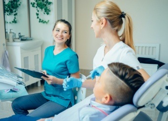 Dental team members examining young child's dental information