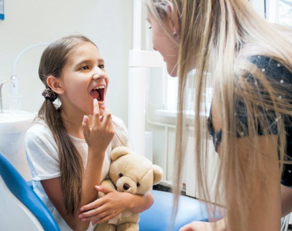 Young patient pointing to smile during children's dentistry visit