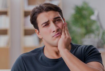 Man in need of emergency dentistry holding jaw in pain