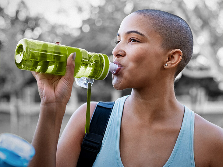 person drinking water outside from a reusable bottle