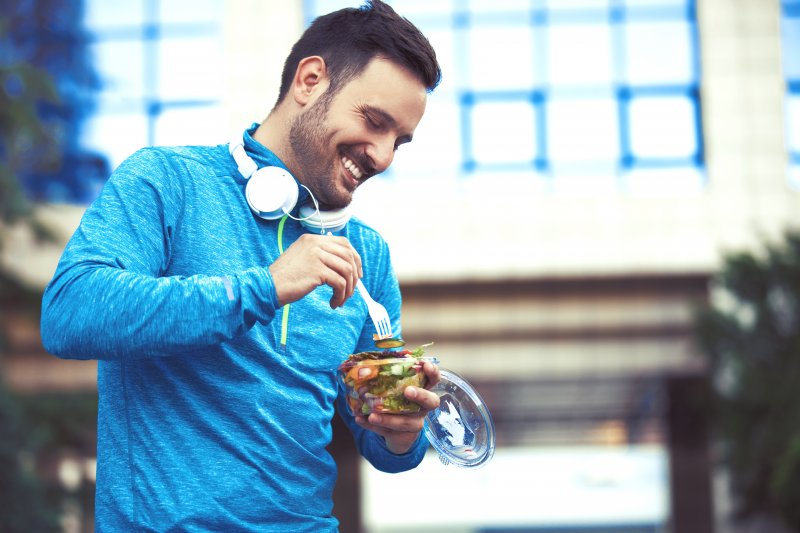 Man with good dental health smiling and eating after exercise