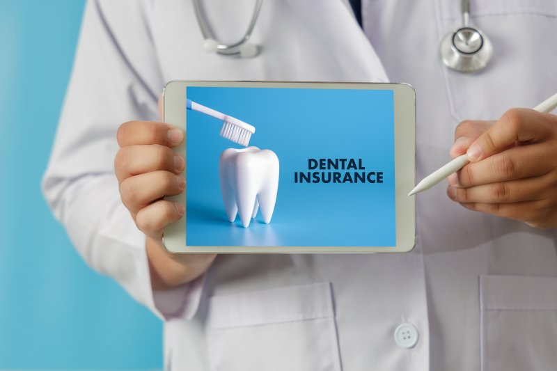 dentist holding tablet with dental insurance written on it